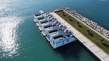 Ein Anwesen am Wasser mit einem Steg, der sich ins Wasser erstreckt, mit mehreren blauen Gebäuden, vermutlich Gästezimmer.