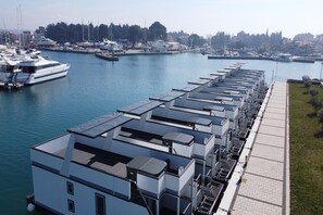 Ein Anwesen am Wasser mit mehreren Gebäuden, einem Yachthafen mit Booten und einem Fußweg.