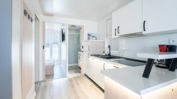 Een moderne keuken met witte kastjes, een ingebouwde oven en een raam met uitzicht op een balkon.