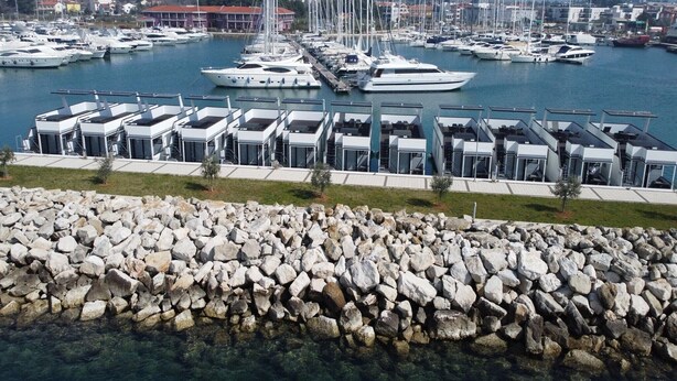 A marina with multiple yachts docked and modern, multi-level buildings with glass facades. - Dream houseboat with sea view and hot tub (Novigrad)