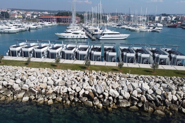 A marina with multiple yachts docked and modern, multi-level buildings with glass facades. - Dream houseboat with sea view and hot tub (Novigrad)