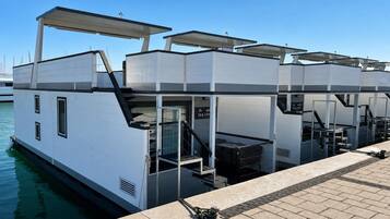 Una estructura moderna flotante con varios niveles, que incluye un comedor y una escalera que conduce a una cubierta superior.