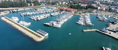 Luchtbeeld van een jachthaven met talloze boten die aanmeren, omringd door een kustplaats.