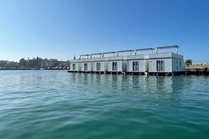 A row of floating houses with a clear view of the water and a distant cityscape.