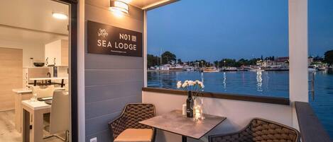 A dining area with a view of the sea, a sign for 'Sea Lodge,' and a table with chairs.