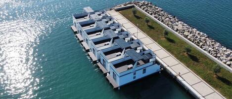 A waterfront property with a dock extending into the water, featuring several blue structures likely to be guest rooms.