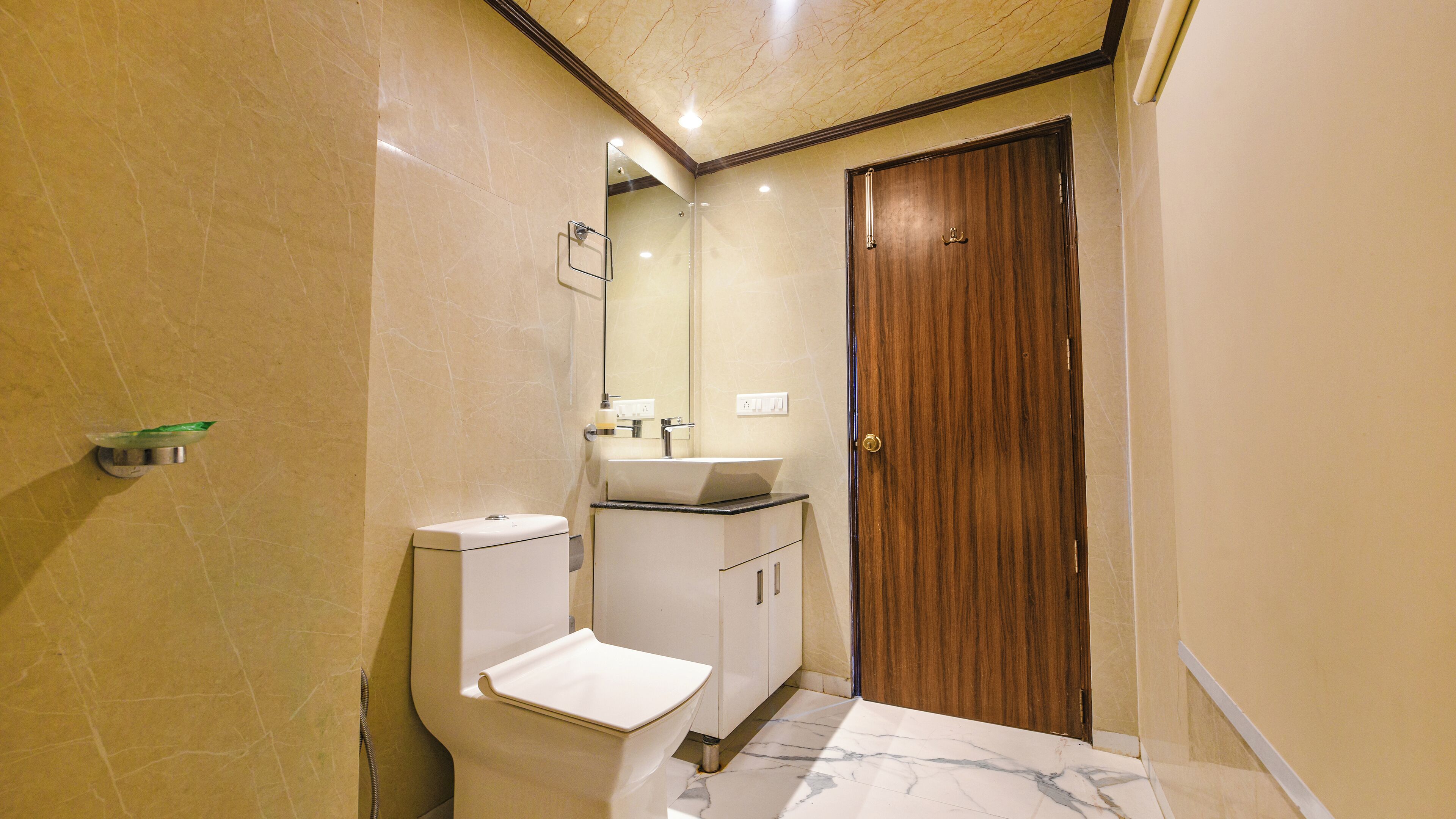 A bathroom with a toilet, sink, and mirror.