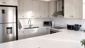 A modern kitchen with stainless steel appliances, a double sink, and a large island.
