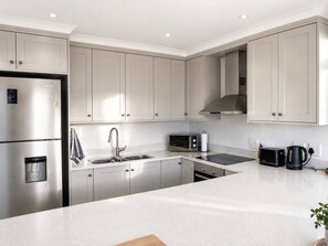 A modern kitchen with stainless steel appliances, a double sink, and a large island.