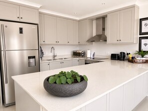 Una cocina moderna con electrodomésticos de acero inoxidable, horno empotrado, microondas y fregadero.