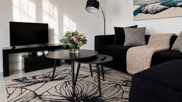 A modern living room with a flat-screen TV, a round coffee table, a sofa, and a painting on the wall.