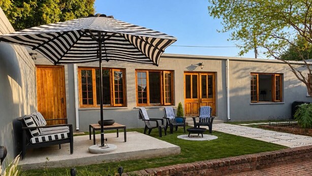 Patioterassi, jossa on ulkokalusteita, nuotiopaikka ja koristeellinen vesielementti.