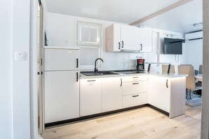 A modern kitchen with white cabinets, a black faucet, a coffee maker, and a flat-screen TV mounted above the counter. - Dream houseboat with sea view and hot tub (Novigrad)