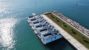 A waterfront property with a dock extending into the water, featuring several blue structures likely to be guest rooms. - Dream houseboat with sea view and hot tub (Novigrad)