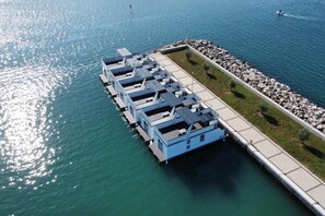A waterfront property with a dock extending into the water, featuring several blue structures likely to be guest rooms. - Dream houseboat with sea view and hot tub (Novigrad)