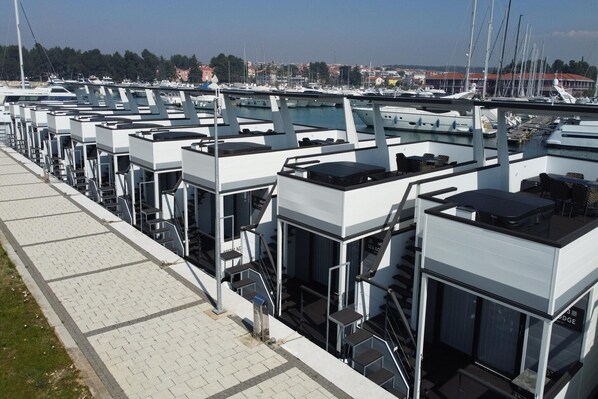 A marina with multiple boats docked, a pedestrian walkway, and a modern building with a staircase. - Dream houseboat with sea view and hot tub (Novigrad)