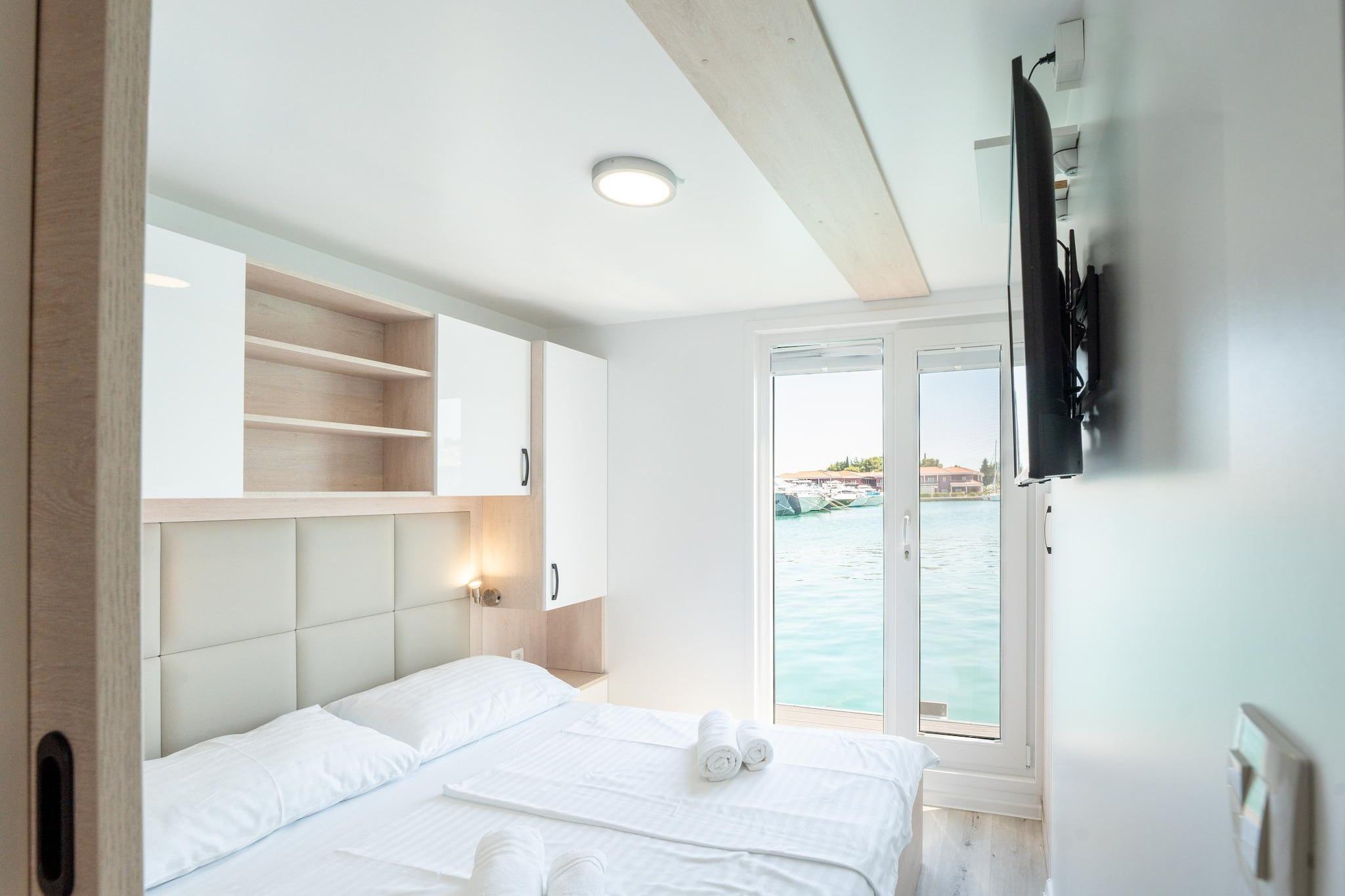 Habitació d'hotel amb llit, televisió i vista al mar.