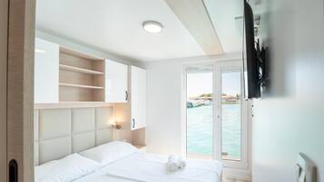 Una habitación de hotel con cama, televisión y vista al mar.