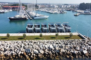 A marina with multiple boats docked, a rocky breakwater, and a row of modern buildings with flat roofs. - Dream houseboat with sea view and hot tub (Novigrad)