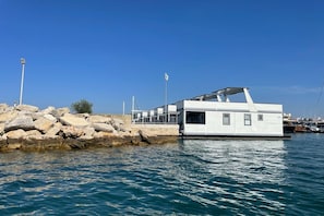 A modern houseboat docked at a marina with a rocky shoreline and clear blue water. - Dream houseboat with sea view and hot tub (Novigrad)
