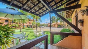 A covered outdoor seating area with tables and chairs, a view of a street, and a building with a tiled roof. - Apt in a Seaside Condominium With a Pool - Gsh2101 (Camaçari)