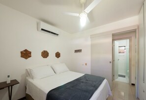 Ein Schlafzimmer mit einem Bett, einem Nachttisch, einem Deckenventilator und einer Tür zu einem Badezimmer.