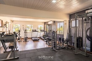 Ein Fitnessraum mit unterschiedlichen Trainingsgeräten, Laufband und Gewichtbank.