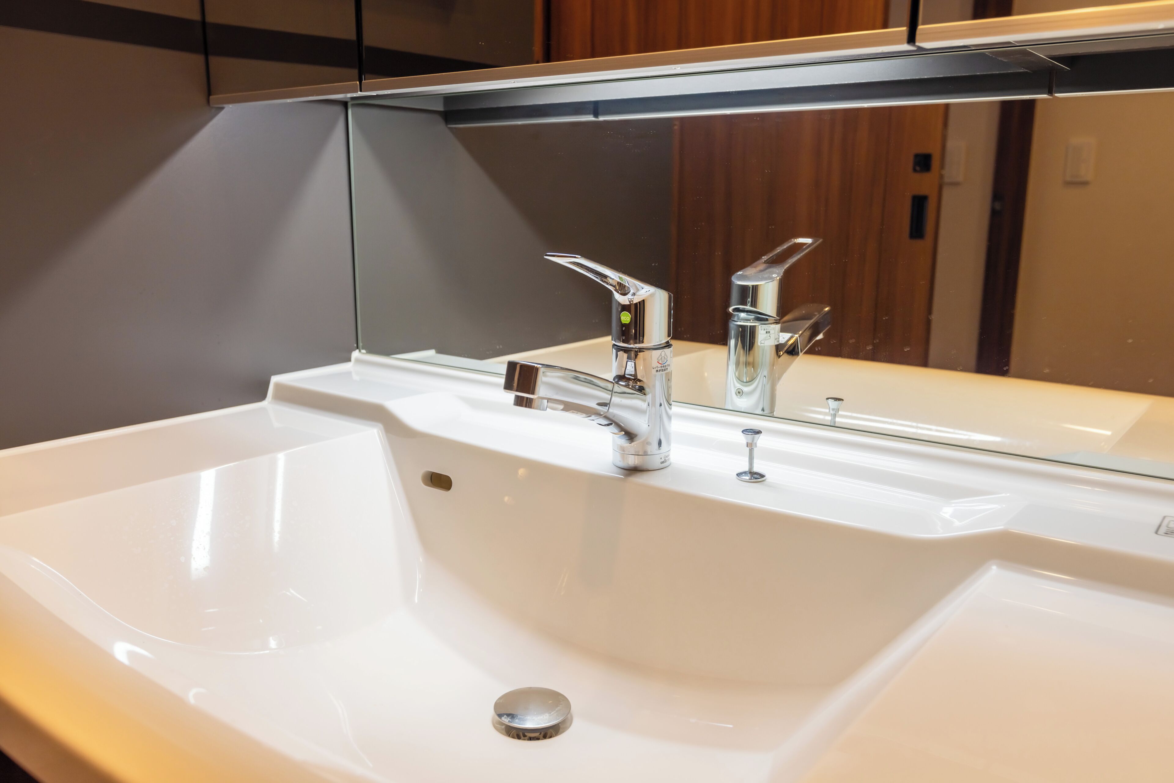 A bathroom with a white sink, chrome faucets, and a mirror above it.