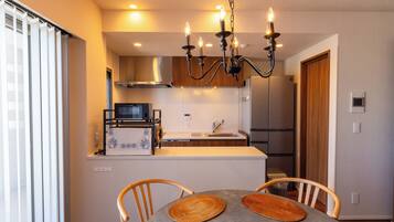 A modern kitchen with a built-in microwave, stove, and refrigerator. There is a dining area with a table and chairs.