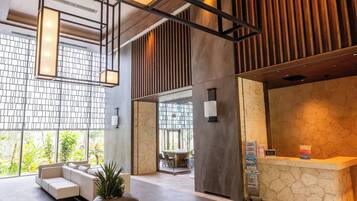 A modern lobby with a reception desk, seating area, and a large window with a view of greenery.