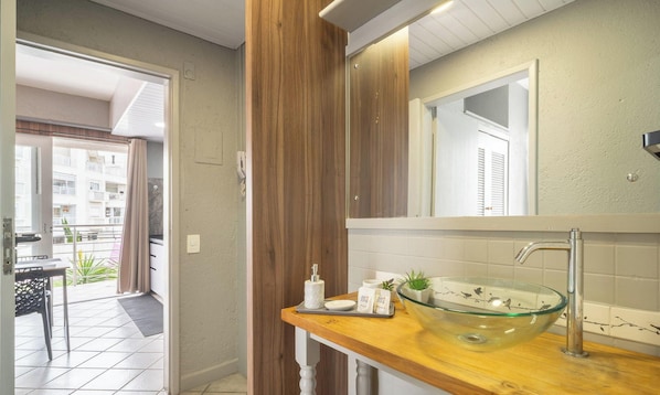 Une salle de bain moderne avec un lavabo en verre, un meuble-lavabo en bois et un grand miroir.