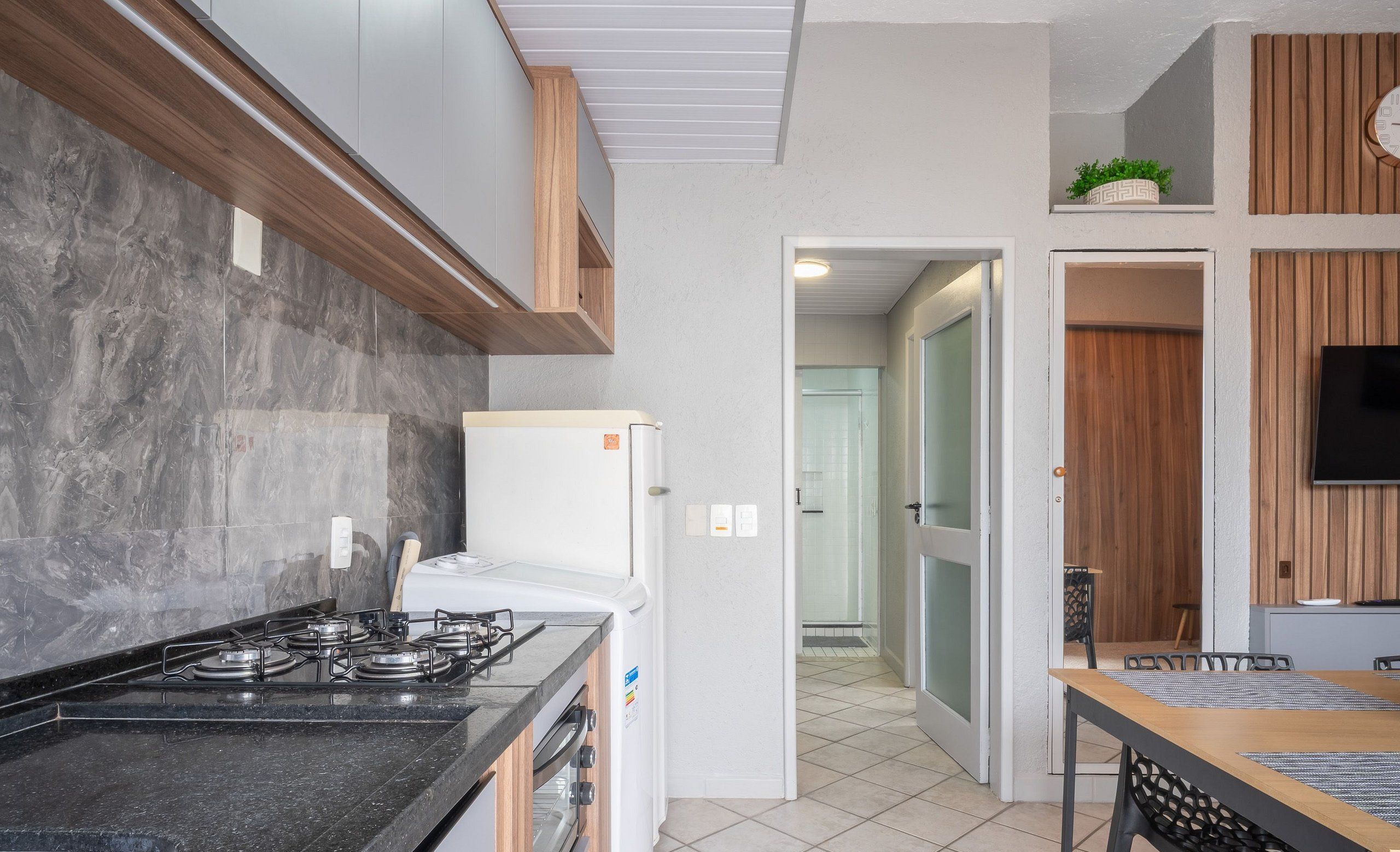 Cocina moderna con estufa a gas, horno integrado y refrigerador. Cuenta con un comedor con mesa y sillas.