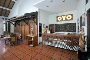 Una habitación con piso a cuadros, un mostrador de recepción de madera y un letrero que dice 'OYO'.
