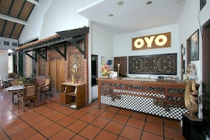 A room with a checkered floor, a wooden reception desk, and a sign that reads 'OYO'.