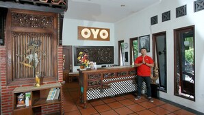 Een receptiegedeelte met een houten receptiebalie, een bordje met de tekst 'OYO' en een betegelde vloer.