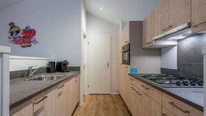 Een moderne keuken met houten kastjes, een RVS spoelbak en een gasfornuis.