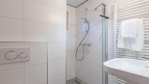 A modern bathroom with a glass-enclosed shower, a white sink, and a towel rack. - Holiday home in Hoogerheide with shared pool (Hoogerheide)