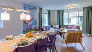 Comedor con una mesa lista para cuatro personas, un sofá y una silla.
