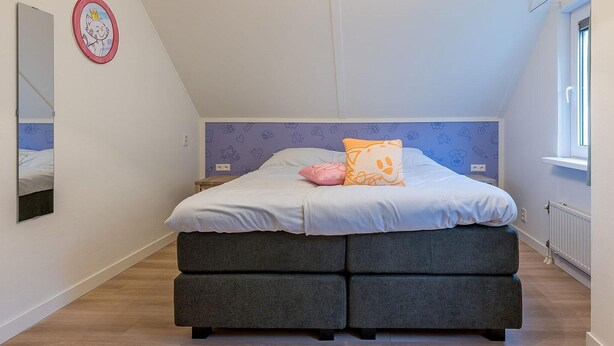 Un dormitorio con una cama, una mesita de noche, un espejo y una ventana.