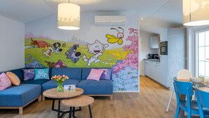 A modern living room with a sectional sofa, a round coffee table, and a vibrant mural on the wall.