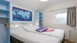 Ein Schlafzimmer mit einem Bett, Wandgemälde mit Nachthimmel, Fenster und Heizkörper.