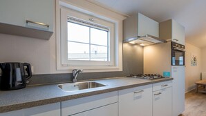 A modern kitchen with a built-in gas stove, a stainless steel sink, and a window above the sink.