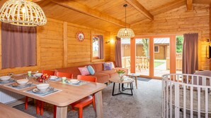 Un interior de madera con una zona de comedor, un sofá y una cuna.