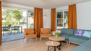 Ein Zimmer mit einer Couch, zwei Sesseln, einem Couchtisch und Blick ins Freie.
