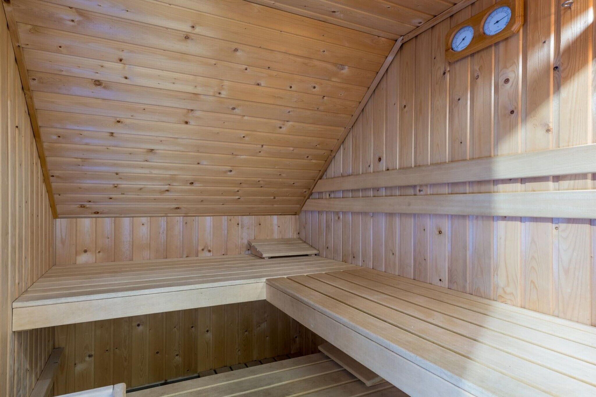 Un sauna aux murs et aux bancs en bois, doté d’un plafond incliné et de deux horloges fixées au mur.