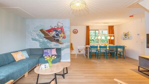 Ein Wohnzimmer mit einer Couch, einem runden Tisch und einem Essbereich mit Stühlen.