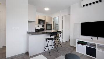 A modern kitchen with a microwave, oven, and a dining area with a TV and seating.