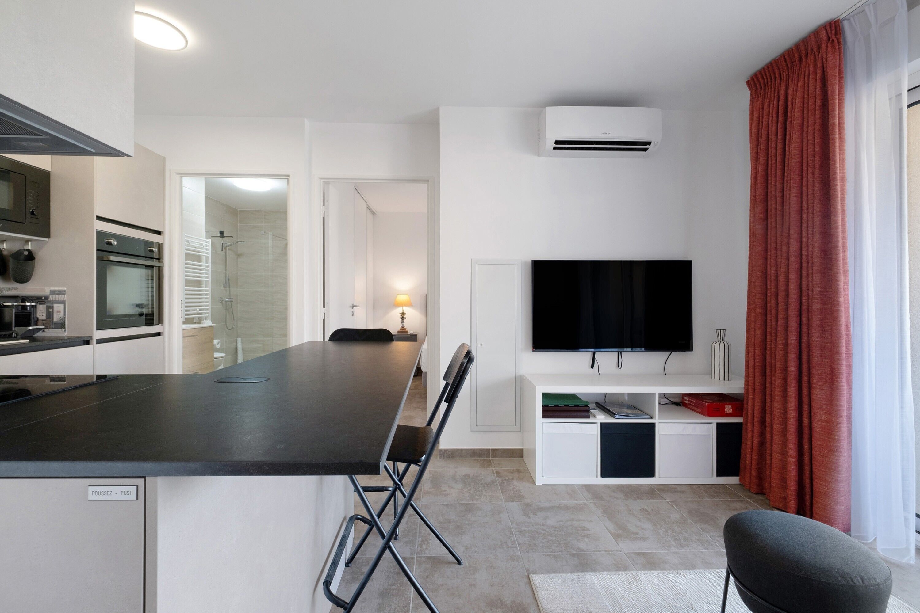 Una cocina moderna con comedor, televisor de pantalla plana y una zona de estar con un mueble para televisión.