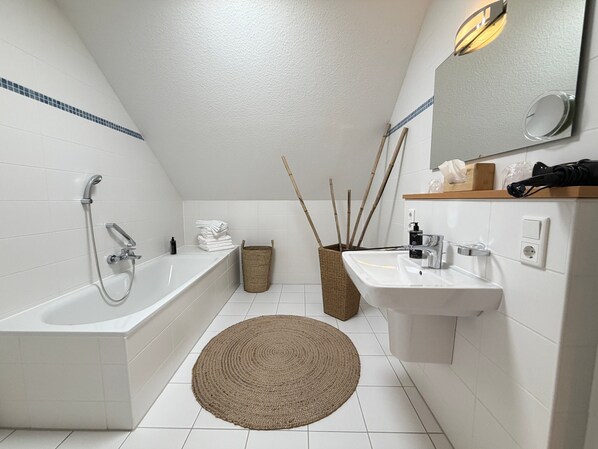 Un bagno moderno con una vasca, un lavandino e uno specchio.