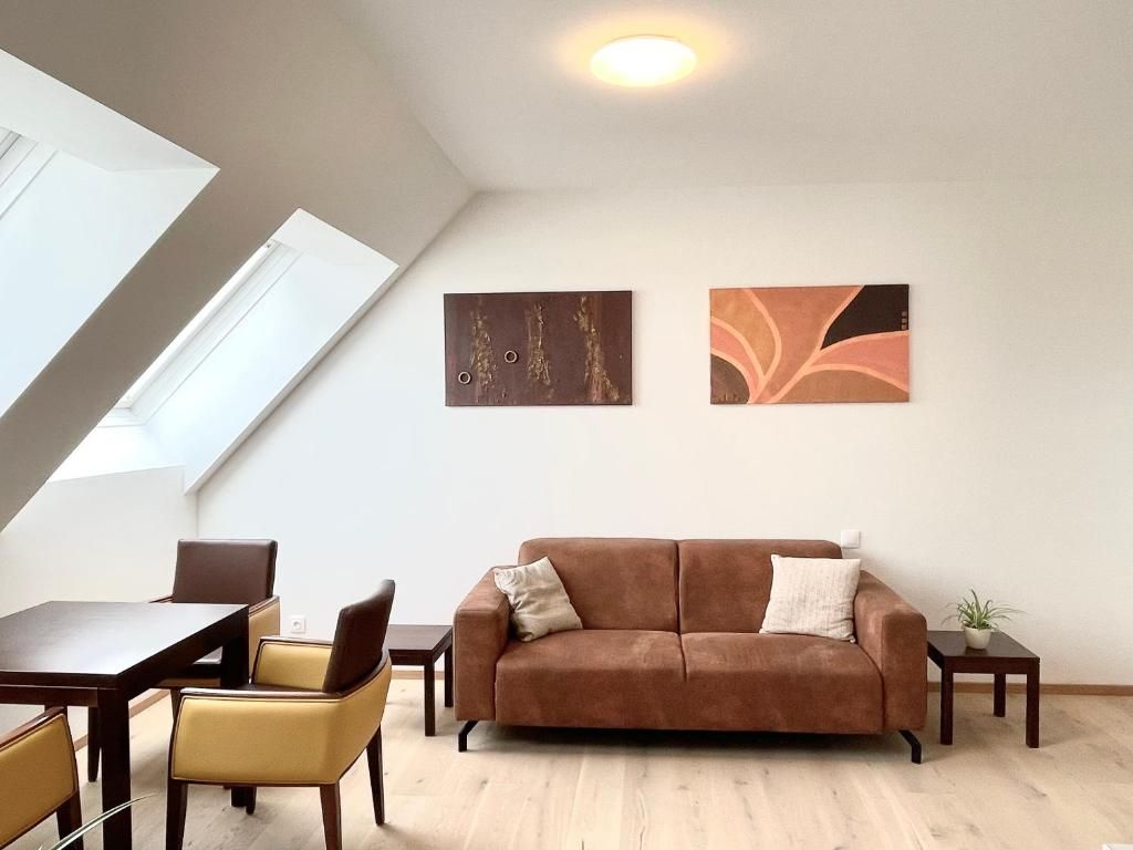 A living room with a brown sofa, a dining table with chairs, and two abstract wall art pieces.